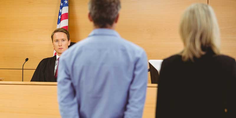 A judge in a courthouse looking at a lawyer and the defendant she's representing after he was bailed out of jail by A-Affordable Bail Bonds in Vancouver, WA