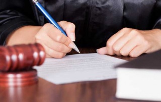 A judge signing papers in a courtroom during a hearing for a client of A-Affordable Bail Bonds, a bail bonds company in Washington State