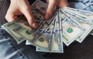 A stack of 100 dollar bills in a woman's hands, representing the bail bonds offered by A-Affordable Bail Bonds in Vancouver, WA