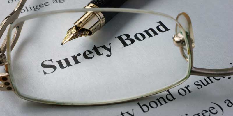 A fountain pen and glasses over a surety bond paper highlighting the surety bond and bail bond services by A-Affordable Bail Bonds in Washington State