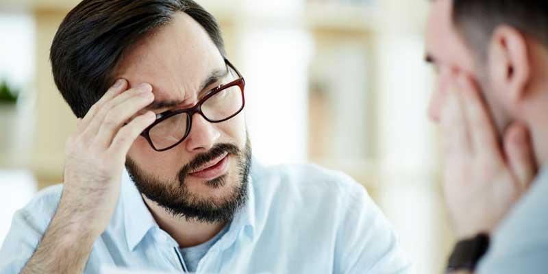 A man sitting in front of another man looking confused representing a person who may have questions about posting bail that can be answered by bondsman company A-Affordable Bail Bonds in Yakima, WA