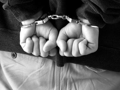 A male with his hands behind his back in handcuffs